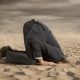 businessman hides his face on the sand