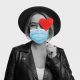 woman holding heart sticker wearing mask