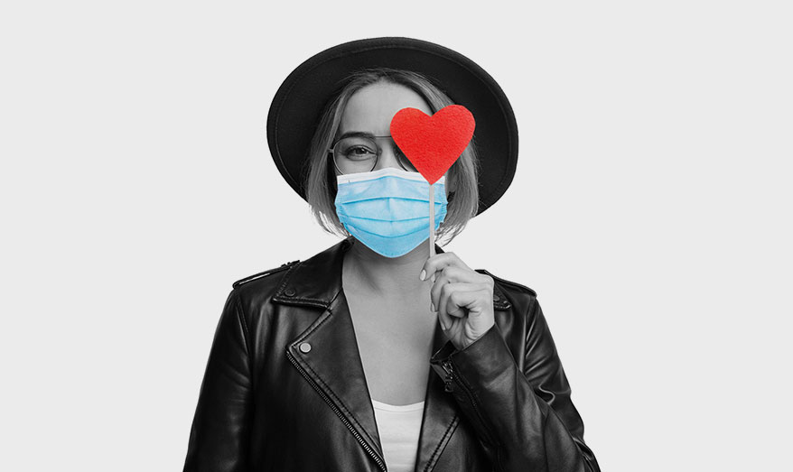 woman holding heart sticker wearing mask